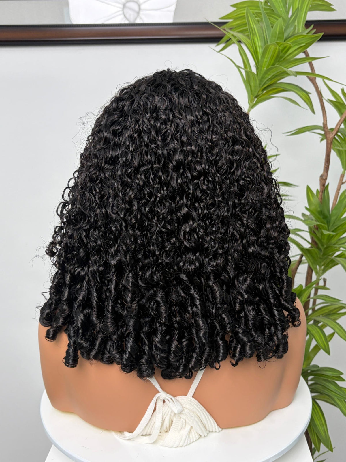 Perruque Olahair mi-longue noire avec boucles serrées et rebondies sur un mannequin, vue de dos